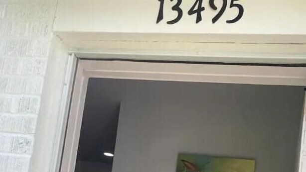 A door with a number 13495 above it, a painting of flowers on the wall, and a glimpse of a room with a bed and a window. - Cozy, Convenient, Modern update (Gonzales)