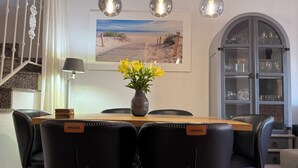 A dining area with a wooden table, black chairs, a vase with yellow flowers, and a painting of a beach scene. - Familienhaus in Cabo Roig in Strandnähe mit Gemeinschaftspool (VC)