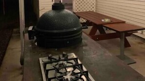 An outdoor patio with a gas stove, a large grill, and a wooden table. - Cozy, Spacious and Clean Home, Close to I-10 (Sorrento)