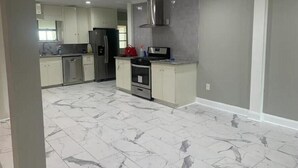 A modern kitchen with white cabinets, a stainless steel refrigerator, a microwave, and a stove. - Cozy, Spacious and Clean Home, Close to I-10 (Sorrento)