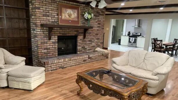 A living room with a brick fireplace, a glass coffee table, and two white sofas. - Cozy, Spacious and Clean Home, Close to I-10 (Sorrento)