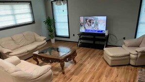 A living room with a beige sofa set, a glass coffee table, and a television on a stand. - Cozy, Spacious and Clean Home, Close to I-10 (Sorrento)