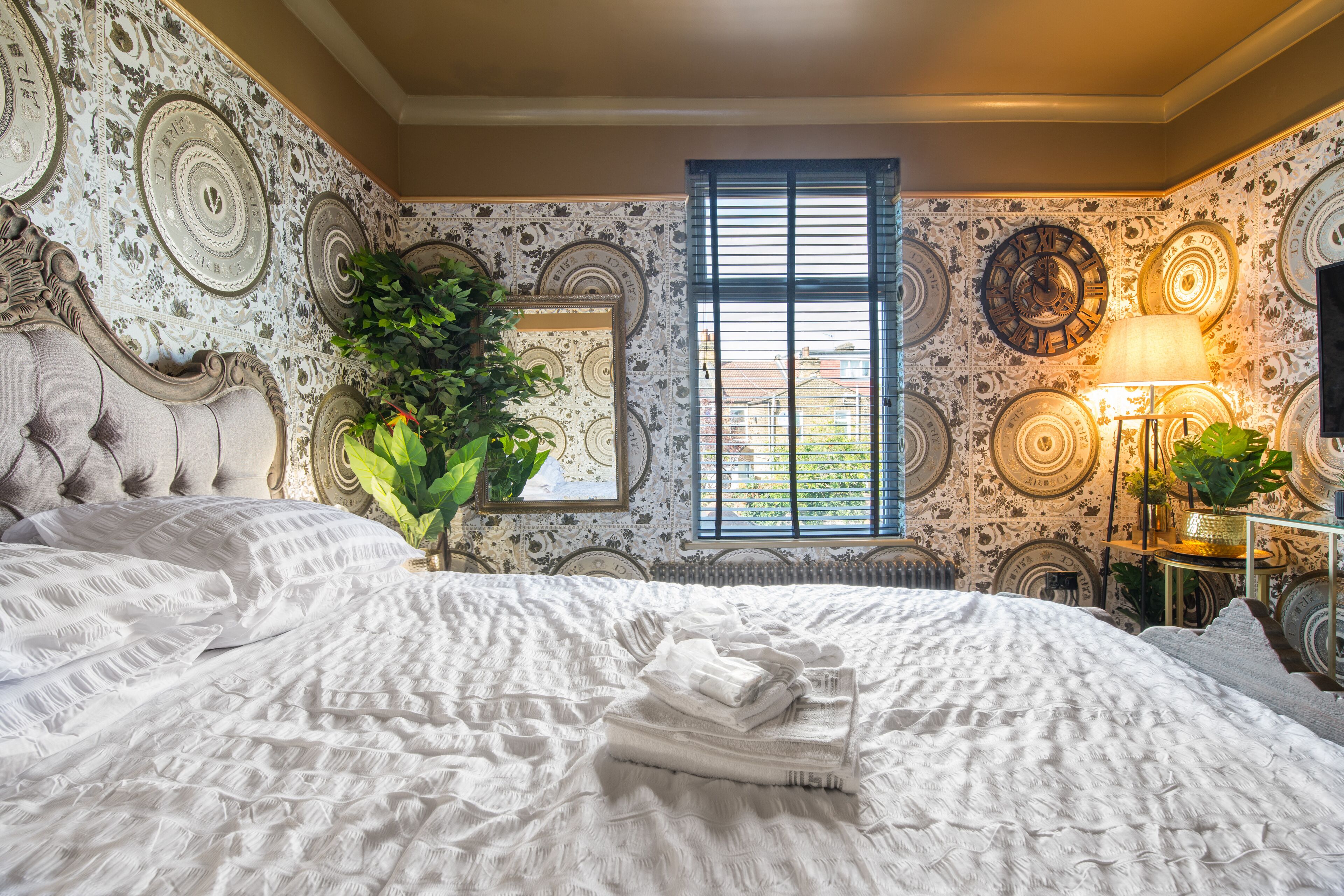 Un dormitorio con una cama grande, una ventana y papel pintado decorativo.