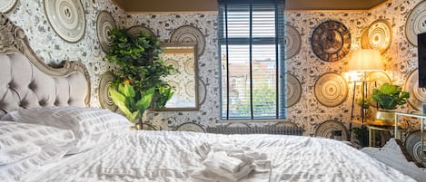 Un dormitorio con una cama grande, una ventana y papel pintado decorativo.