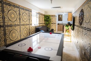 A room with a shuffleboard table, a potted plant, and patterned wallpaper. - Luxury Versace 1 Bed, Hot Tub, Pool Table, Sky Tv (Greater London)