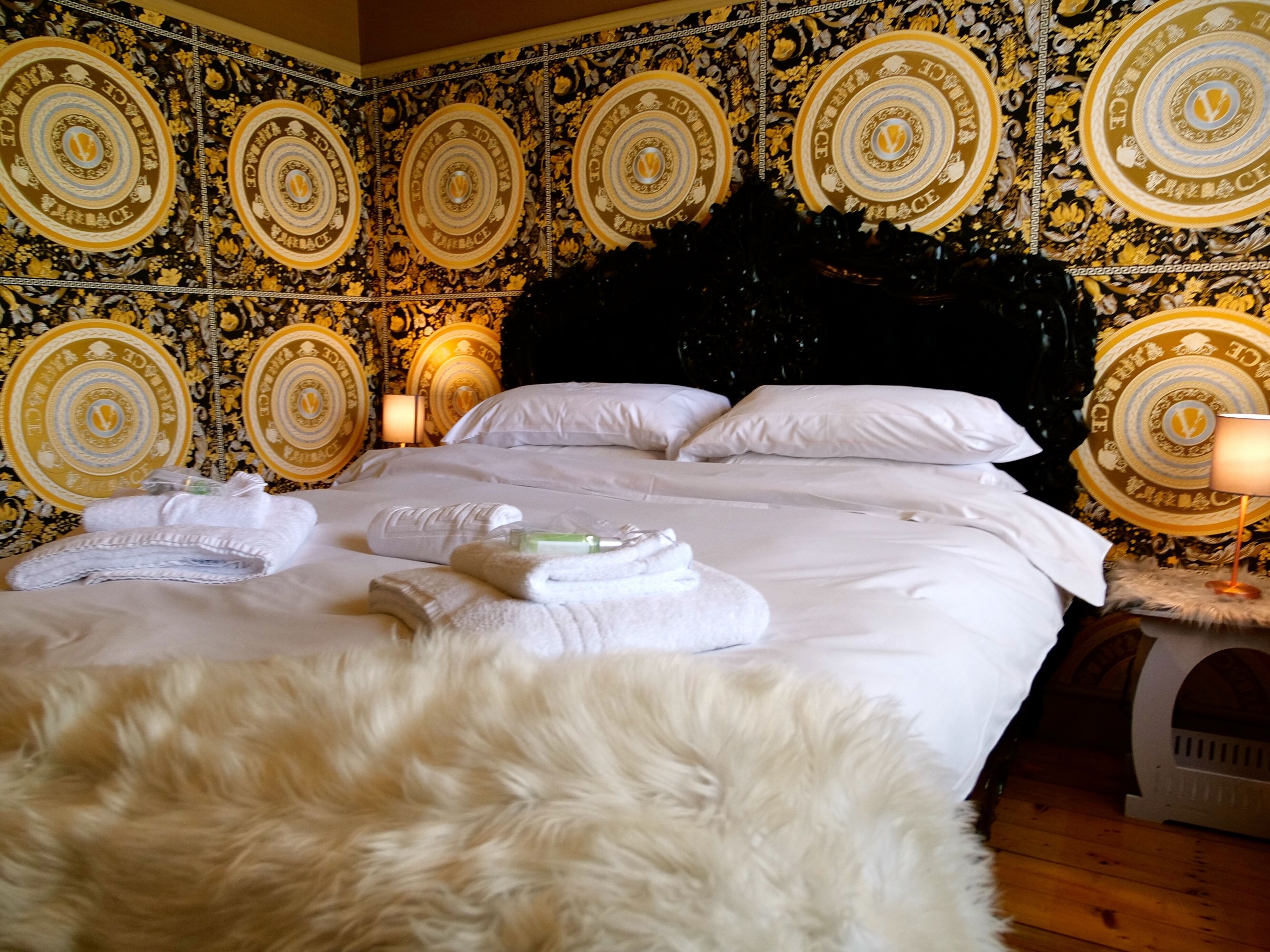 Een hotelkamer met een groot bed, witte lakens en een zacht, wit vloerkleed.