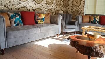 Una sala de estar con un sofá gris, sillones y una mesa de centro con base de madera.
