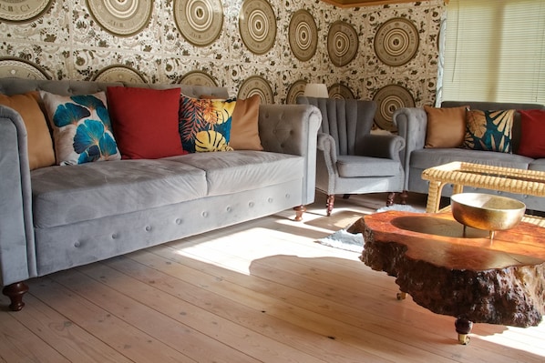 A living room with a grey sofa, armchairs, and a coffee table with a wooden base.