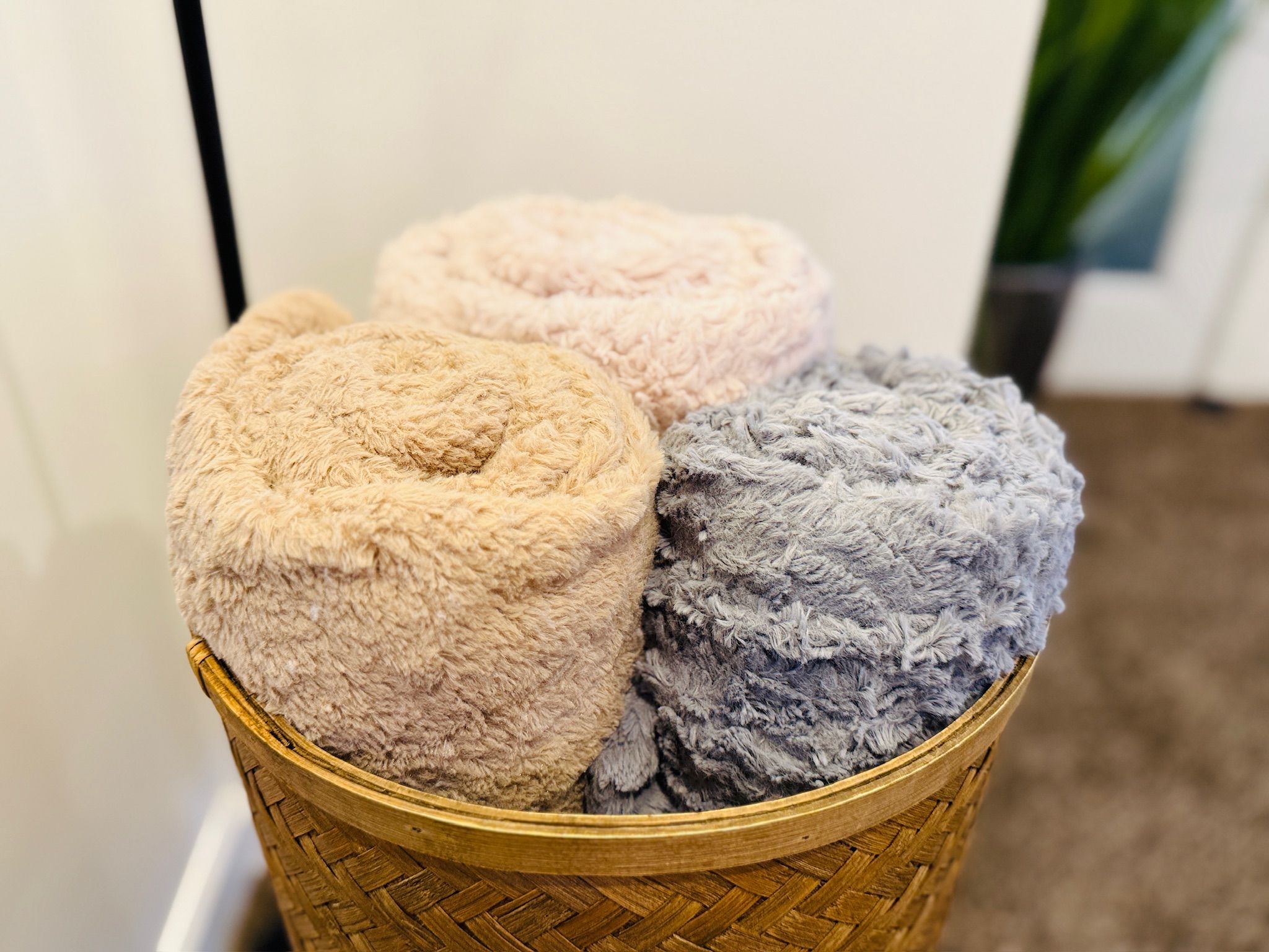 A basket containing three plush, circular cushions in neutral tones.