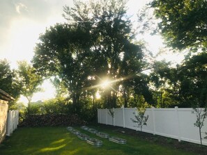 Ein Garten mit weißem Zaun, Rasen und Bäumen.