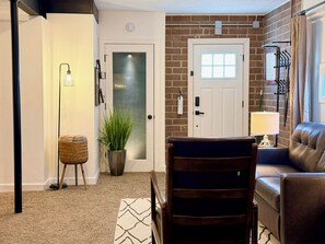 Un salon avec un canapé en cuir marron, une chaise en bois foncé, un lampadaire et une plante en pot.