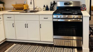 Una cocina moderna con armarios blancos, una estufa de acero inoxidable, un microondas y un lavamanos.