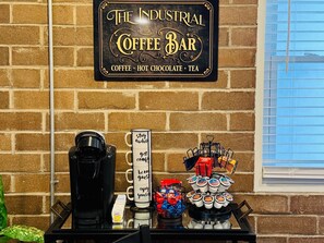 Letrero de una cafetería con una máquina de café, condimentos y bocadillos.