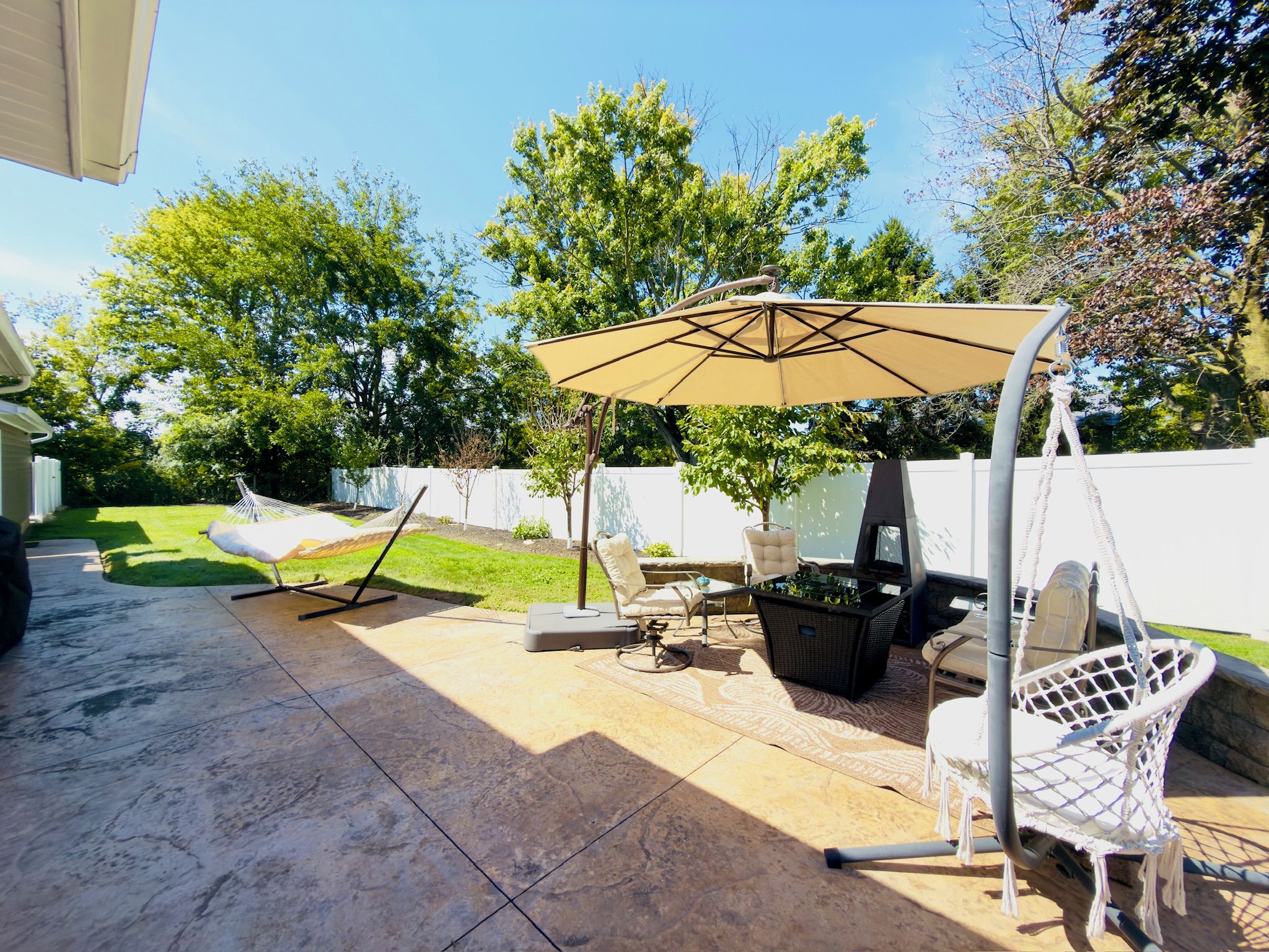 A patio with outdoor furniture, a swing chair, and a large umbrella.