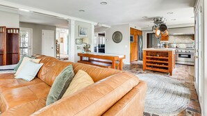 Un soggiorno spazioso con un divano in pelle, un'area pranzo con tavolo in legno e una cucina con elettrodomestici moderni.