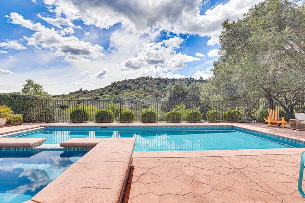 A swimming pool with clear blue water, surrounded by a stone deck and a metal fence. - Escondido Home: Private Pool, 2 Grills & Fire Pit! (Escondido)