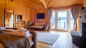 Een houten kamer met een bed, een stoel, een televisie en een stenen open haard.