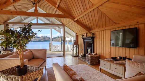 Een gezellig interieur met hout, een grote televisie, comfortabele zitplaatsen en een open haard.