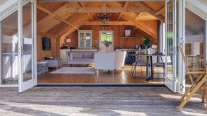 Een open loft met hoge plafonds, houten balken, een keuken, een woonkamer met een bank en een eethoek.
