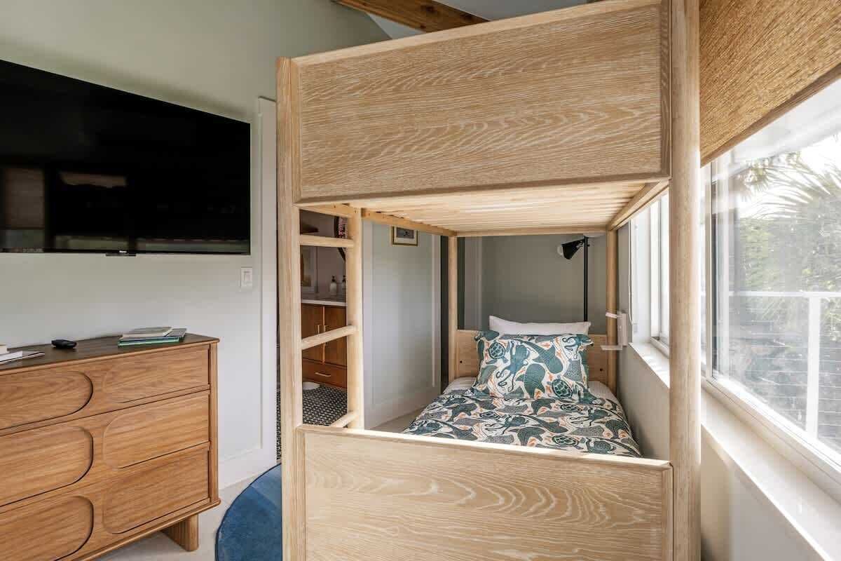 Une petite pièce avec un lit superposé, une commode en bois et une fenêtre donnant sur l’extérieur.