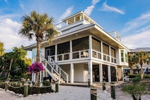 A modern coastal building with a balcony, large windows, and a staircase leading to the entrance. - Lookout Escape: Heated Pool, Free Golf Cart, Outdoor Bar, Gulf Views (North Captiva)
