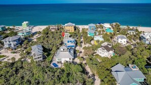 An aerial view of a coastal residential area with houses, a beach, and a clear blue sky. - Lookout Escape: Heated Pool, Golf Cart, Outdoor Bar, Gulf View (North Captiva)