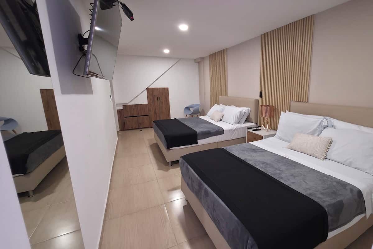 A hotel room with two beds, a wooden wardrobe, a desk, and a chair.