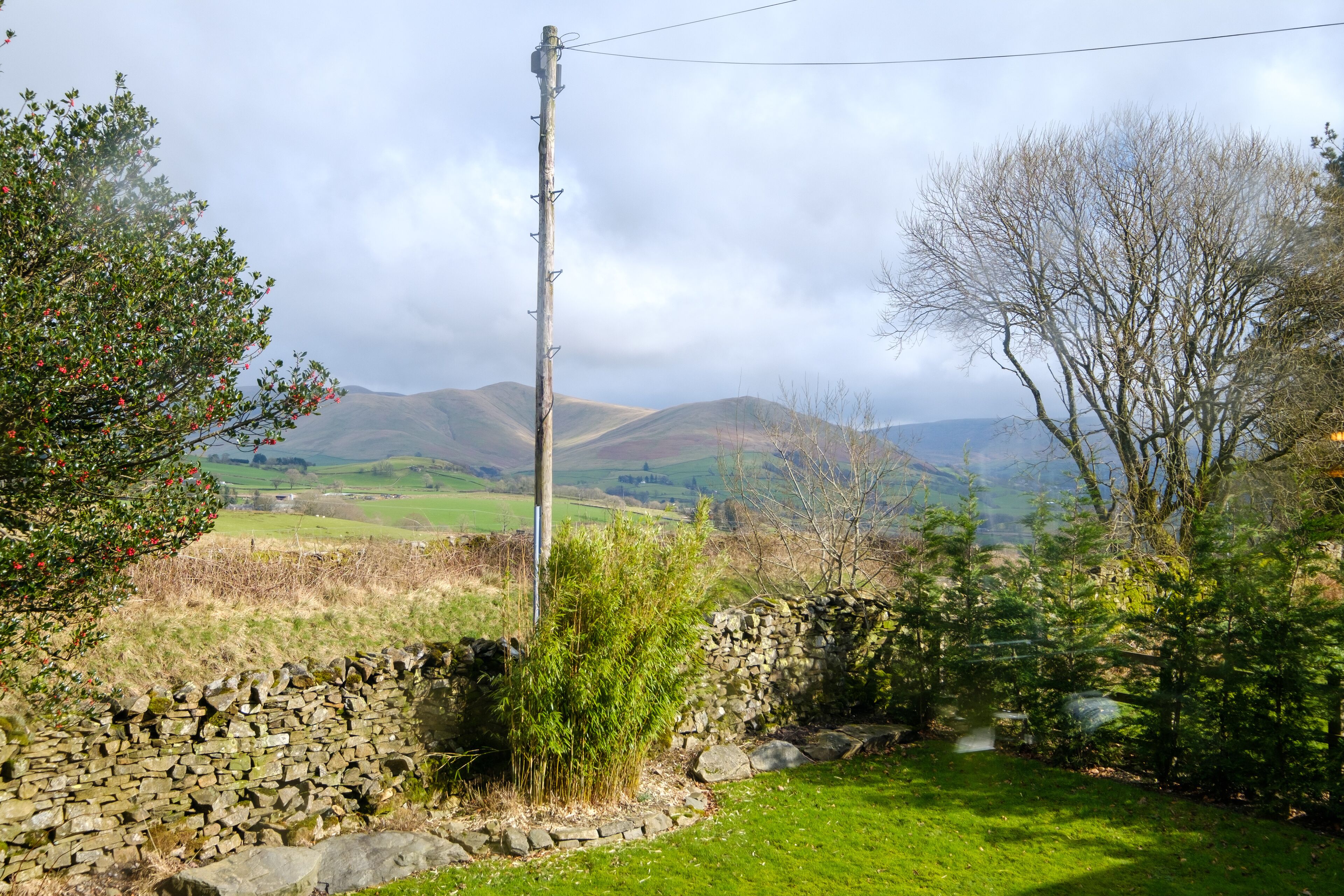 A stone wall, a grassy area, and a mountain range in the background.