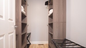 Un couloir étroit, avec des étagères en bois de chaque côté, un présentoir en métal noir au centre et une porte blanche sur la gauche.