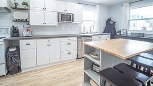 Une cuisine moderne avec des meubles blancs, un four à micro-ondes et une table à manger en bois.