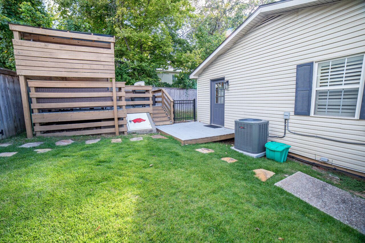 A backyard with a wooden deck, a small concrete patio, and a house with a gray exterior.