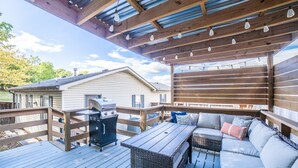 A covered deck with a grill, outdoor seating, and a view of a house. - The Garland Getaway - Short Walk to UofA (Fayetteville)