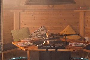 A wooden interior with a table set for dining, featuring a grill and plates.