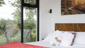 A hotel room with a large window offering a view of trees and a distant building.