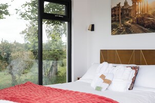 A hotel room with a large window offering a view of trees and a distant building.