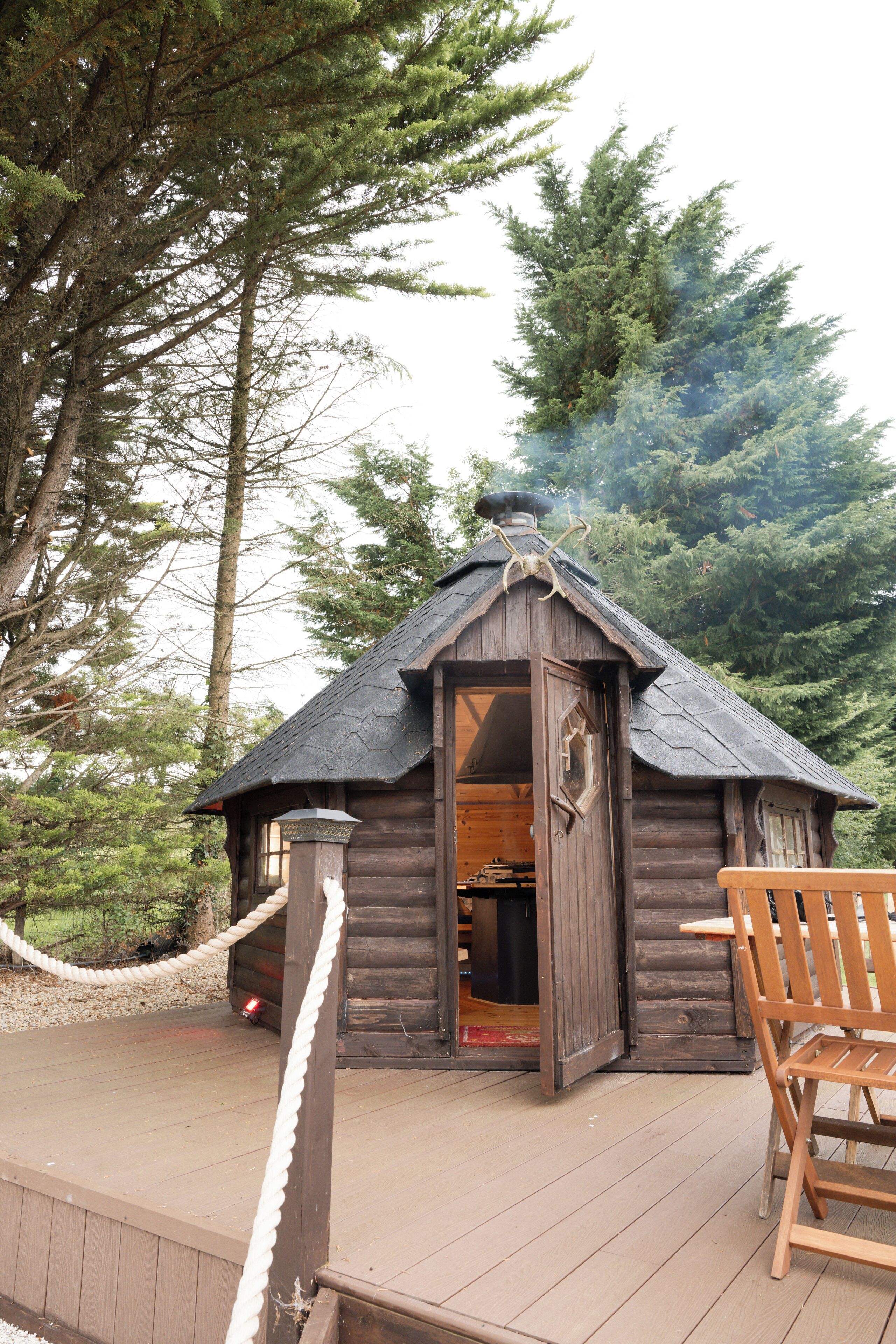 A wooden cabin with a sloped roof, a rope barrier, and a wooden deck.