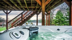 Ein Whirlpool unter einer Holzterrasse mit einer Treppe, die zu einem Haus führt.