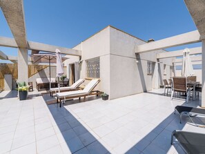 A rooftop terrace with sun loungers, a table, and umbrellas. - Cosy apartment for 6 people with A/C, WIFI, TV and terrace (Salou)