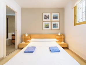 A bedroom with a bed, two bedside tables, a nightstand, a window, and four framed pictures on the wall. - Cosy apartment for 6 people with A/C, WIFI, TV and terrace (Salou)