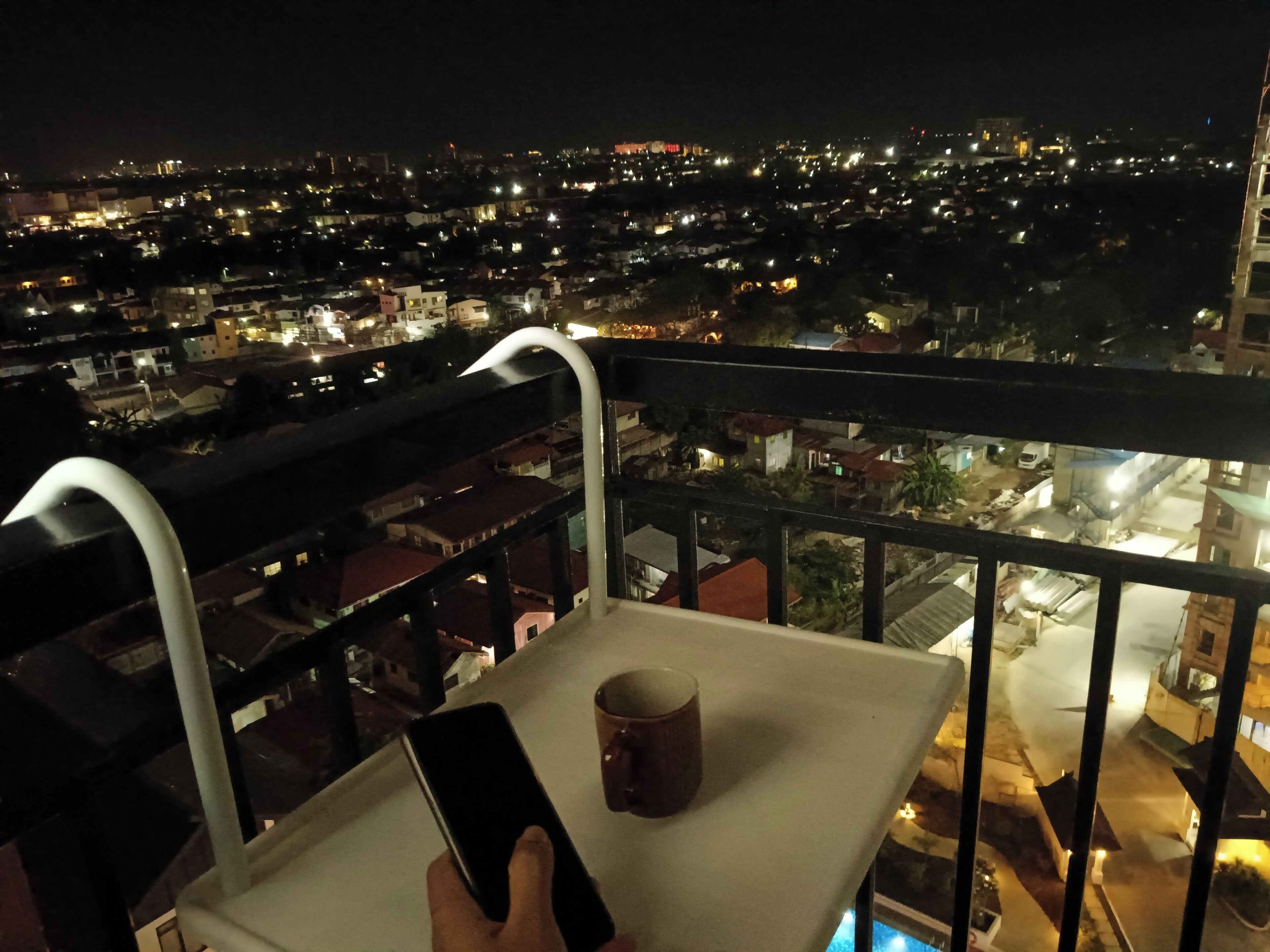 A balcony with a railing, a table, and a smartphone.