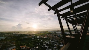 A view from a balcony with a wooden structure, overlooking a densely populated area with various buildings and greenery.