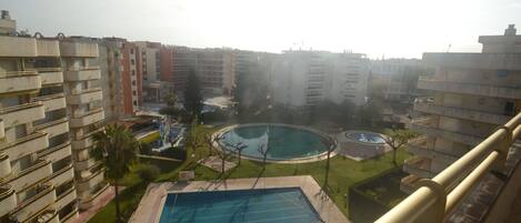 Zona residencial con piscina, cancha de baloncesto y cancha de tenis, todo rodeado de edificios de apartamentos.