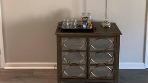 En bardisk med en dekorativ skylt, en lampa och ett bricka med glas och snacks.