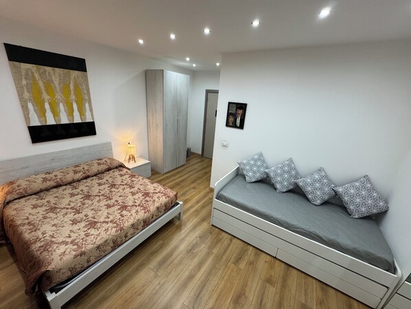 A modern bedroom with a large bed, a sofa bed, a wardrobe, and a painting on the wall. - Aria di Casa Experience - Independent room with private bathroom (Cassino)