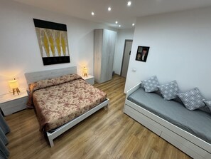 A bedroom with a double bed, a sofa bed, two bedside tables with lamps, a wardrobe, and a painting on the wall. - Aria di Casa Experience - Independent room with private bathroom (Cassino)