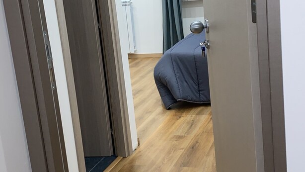 A hallway leading to a bedroom with a bed, a window with curtains, and a door. - Aria di Casa Experience - Independent room with private bathroom (Cassino)