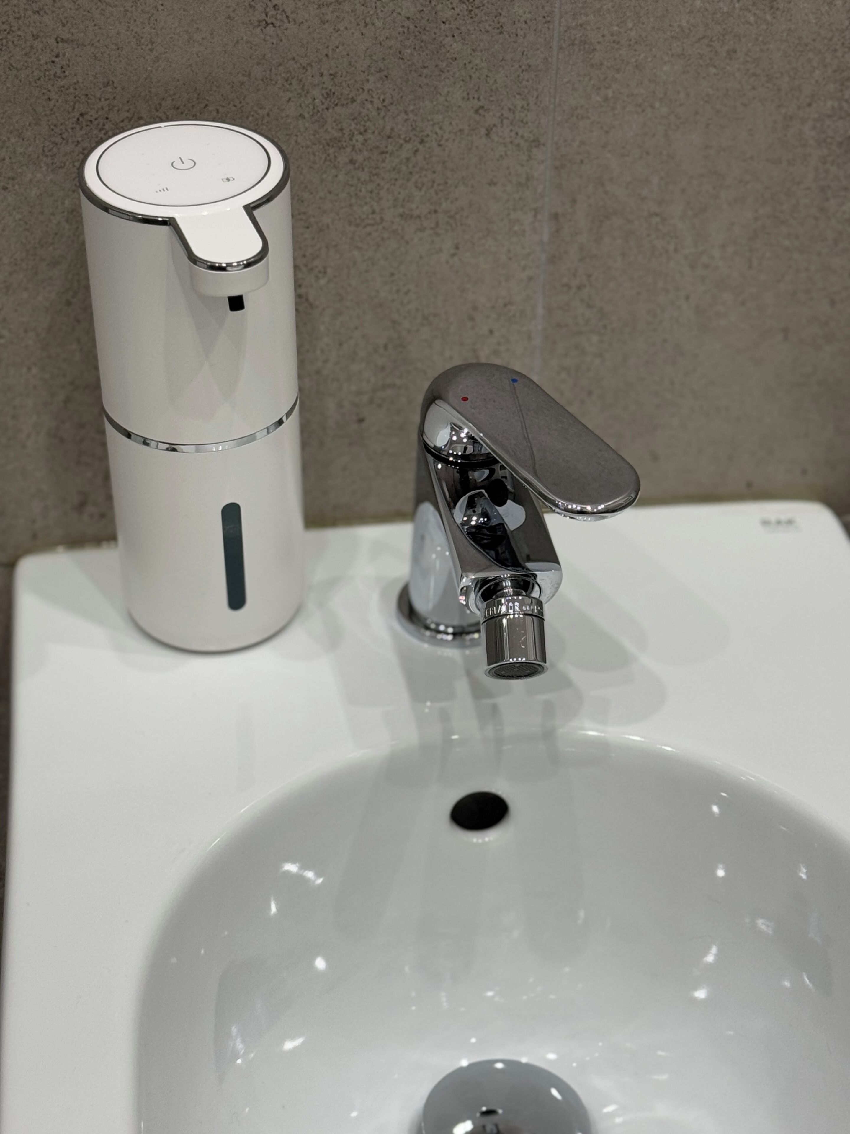 Ein Waschbecken mit einem chromfarbenen Wasserhahn und einem weißen Wasserkocher.