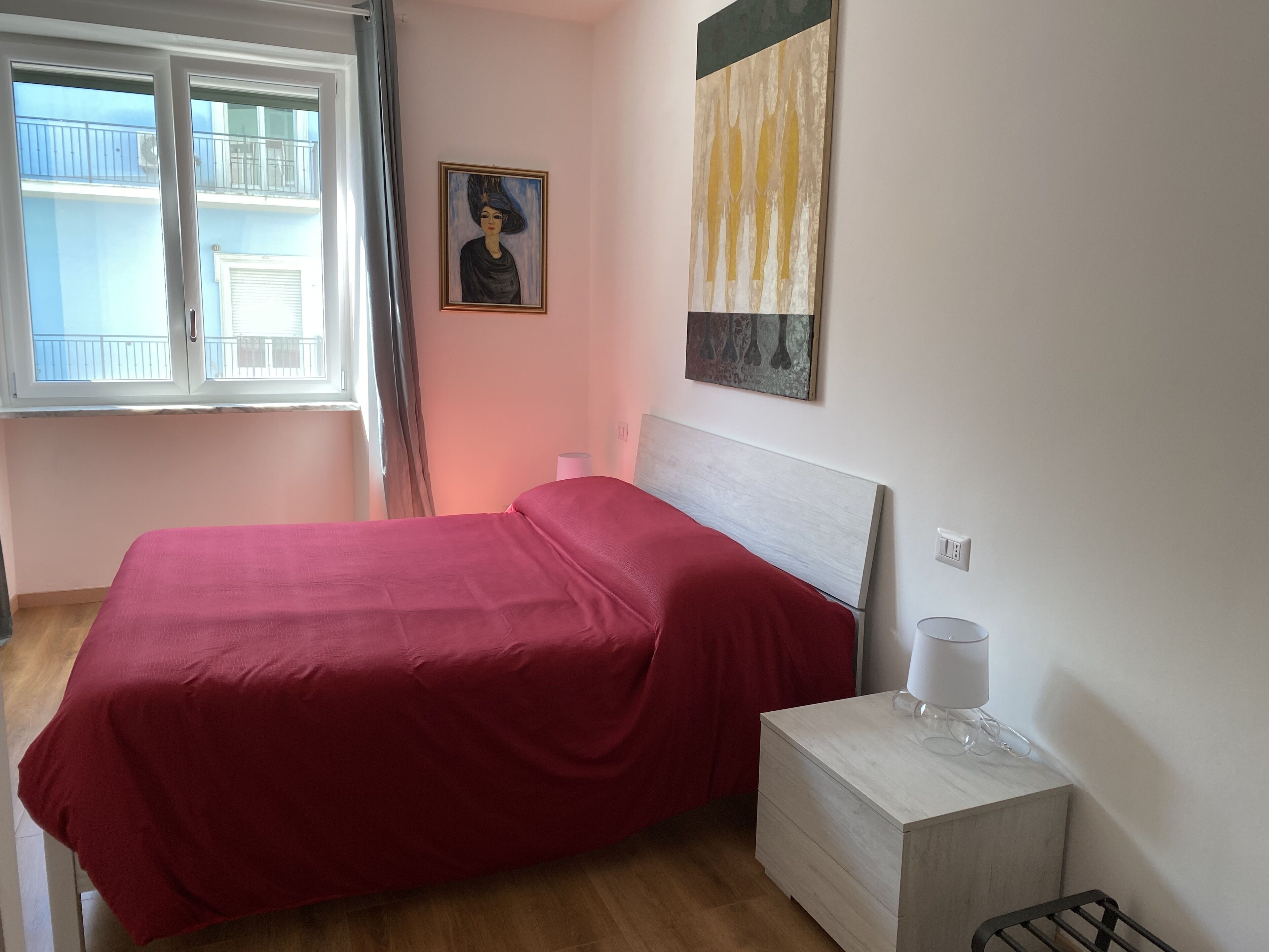 Un dormitorio con una cama, una mesita de noche, una lámpara y un cuadro en la pared.