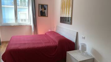 Un dormitorio con una cama, una mesita de noche, una lámpara y un cuadro en la pared.