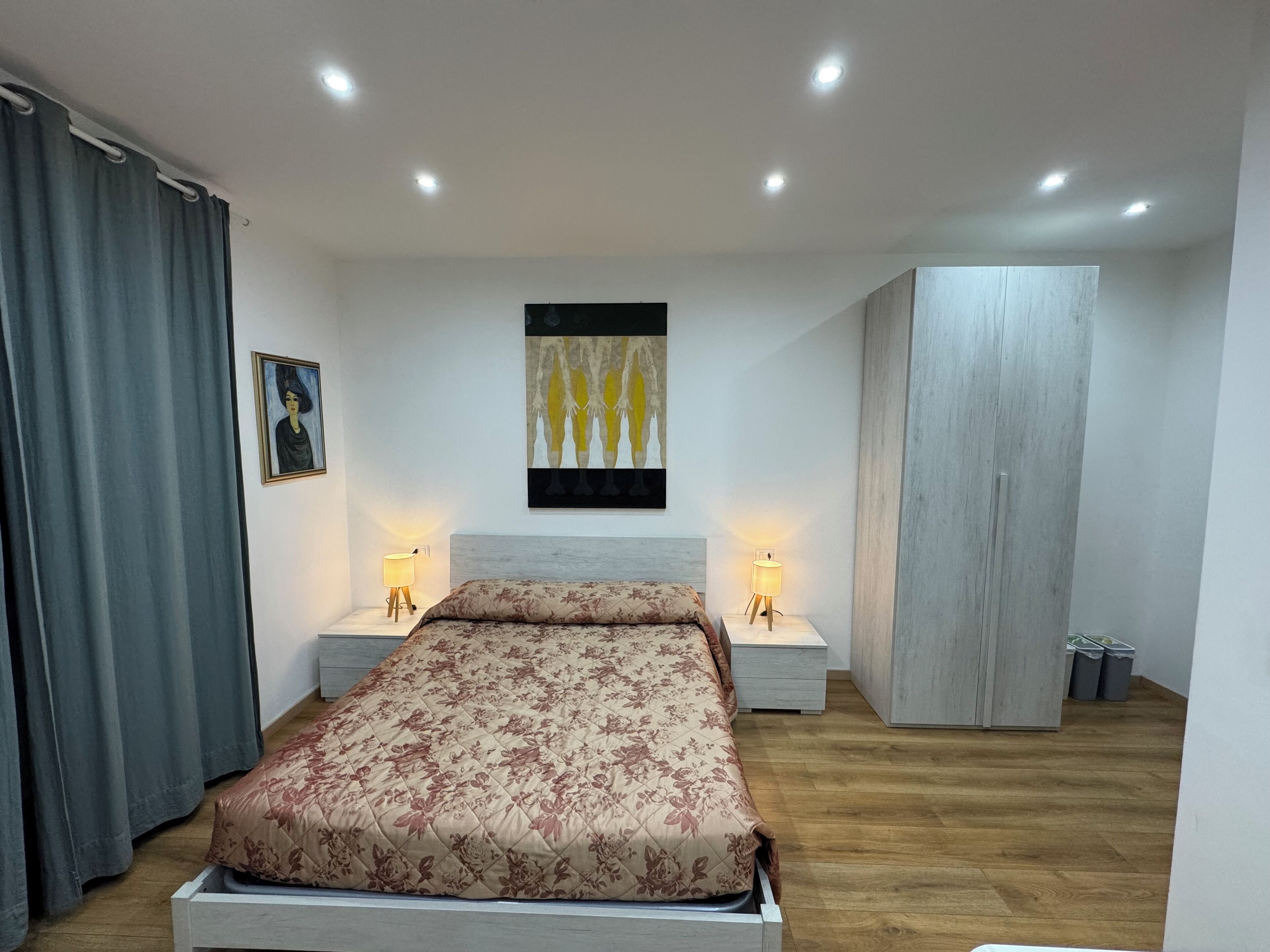 Ein Schlafzimmer mit einem Bett, zwei Nachttischlampen, einem Gemälde und einem Kleiderschrank.